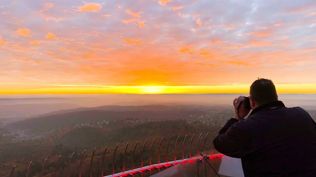 Person photographing sunset from Fernsehturm Stuttgart observation deck.