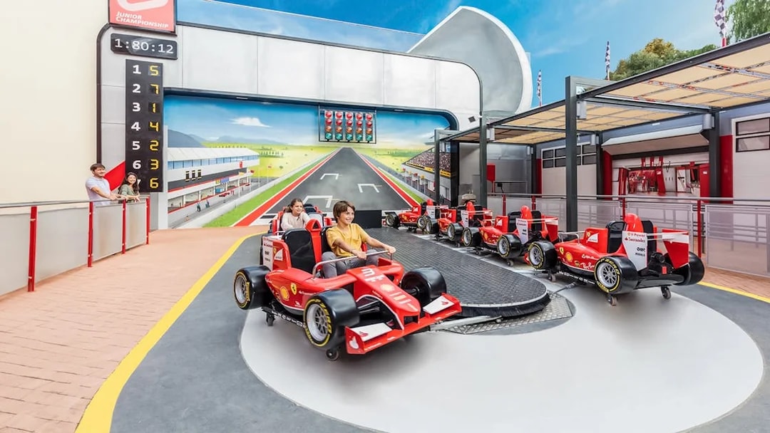 Junior championship ride at Ferrari Land with children in red race cars.
