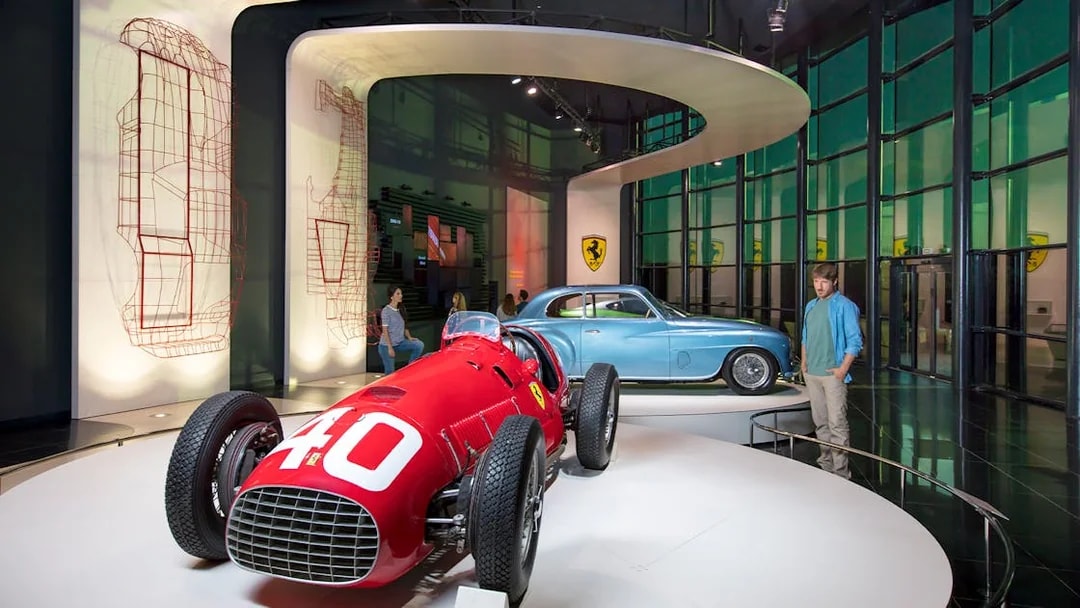 Man observing classic Ferrari cars in Ferrari Land exhibit.