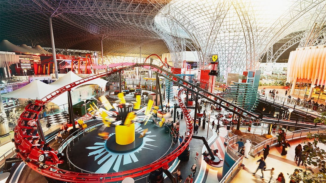 Ferrari World Abu Dhabi indoor roller coaster with vibrant red tracks and visitors exploring.