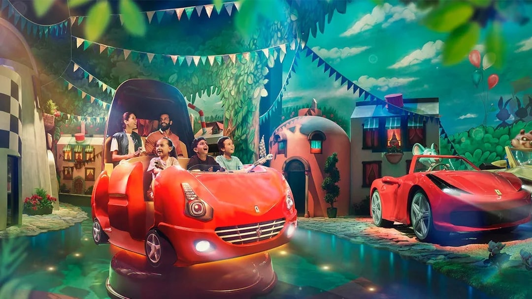 Visitors enjoying a ride at Ferrari World Abu Dhabi with vibrant decor and Ferrari-themed cars.