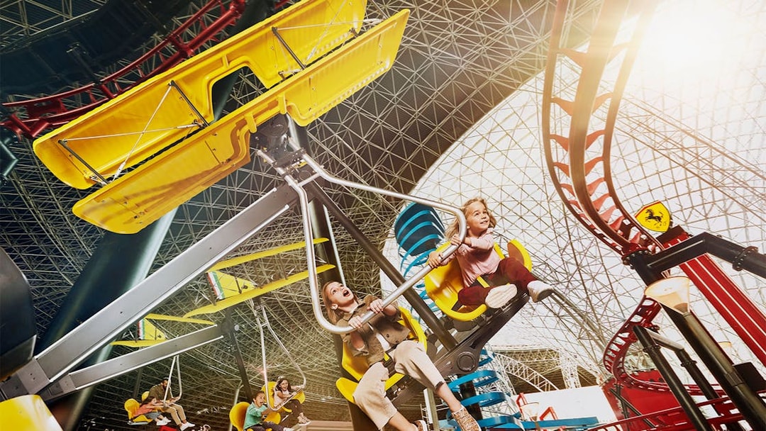 Visitors enjoying a ride at Ferrari World Abu Dhabi under the iconic roof structure.