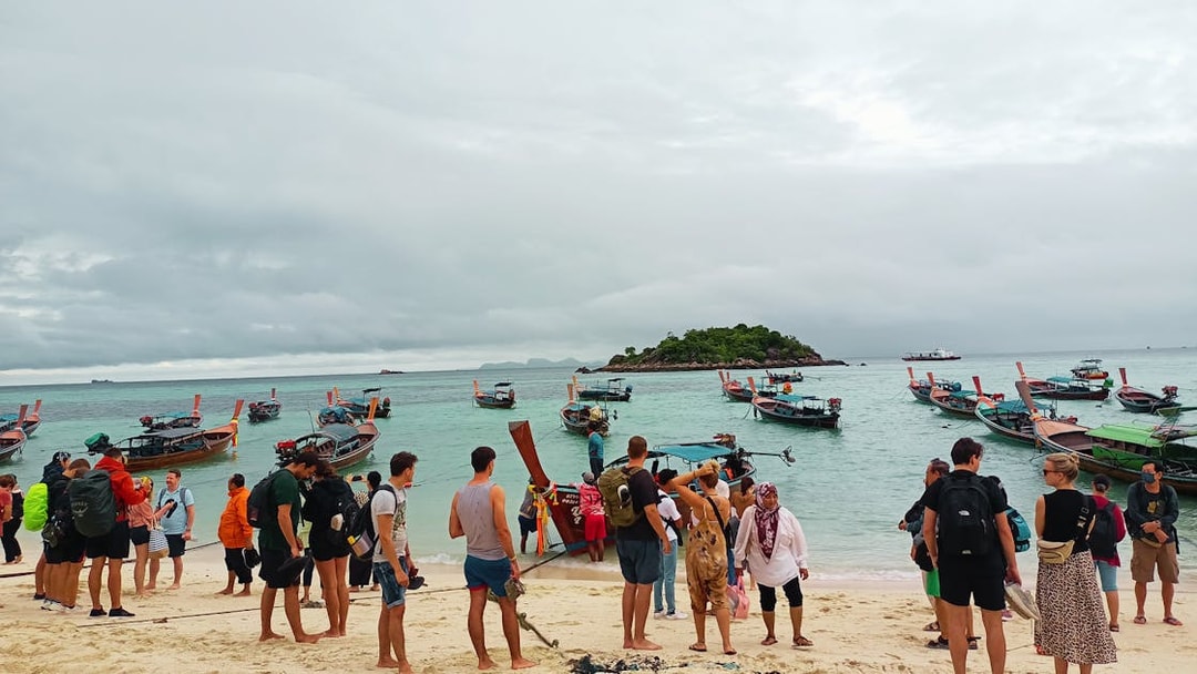 Tourists boarding long-tail boats at Koh Lipe beach for ferry to Telaga Harbour Langkawi.