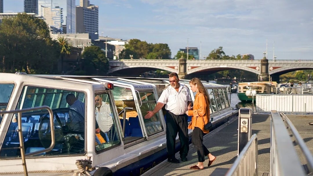 Cruise captain checking guest tickets on Yarra River sightseeing cruise in Melbourne.