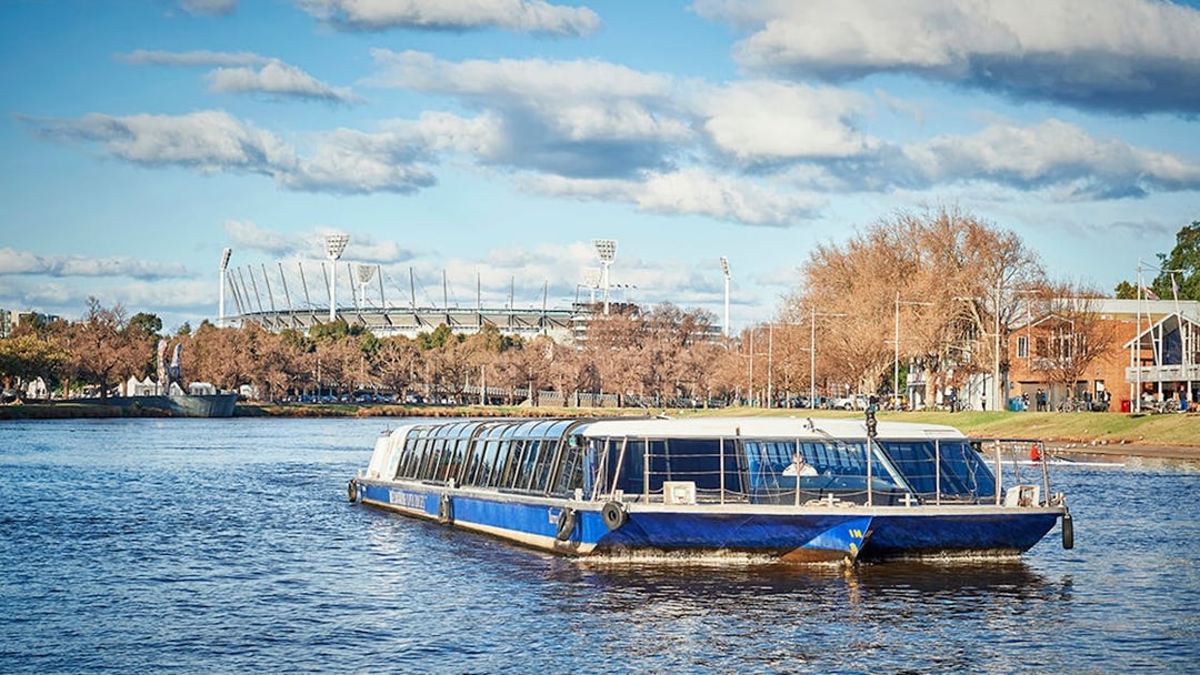 Ferry cruising on Yarra River with Melbourne Cricket Ground in the background.