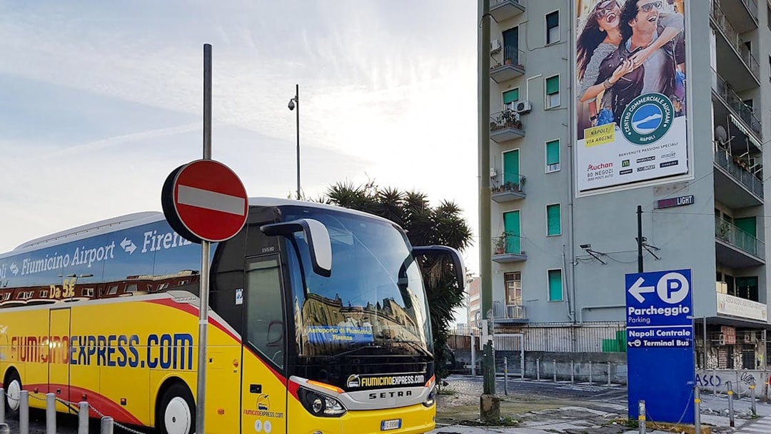 Fiumicino Express bus parked near Naples Centrale sign.