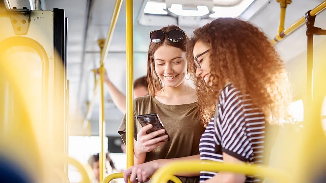 Two women on a bus checking phone, Fiumicino Airport to Naples transfer.