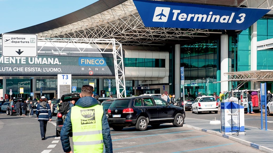 Fiumicino Airport Terminal 3 entrance with cars and travelers, Rome, Italy.