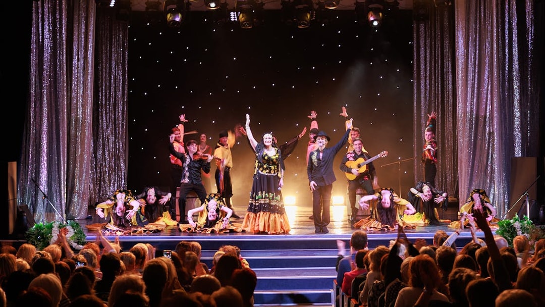 Flamenco dancers performing on stage in Granada with audience watching.