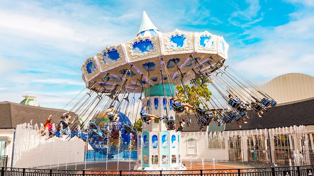 People enjoying a carousel ride at Dreamworld with fountains in the foreground.