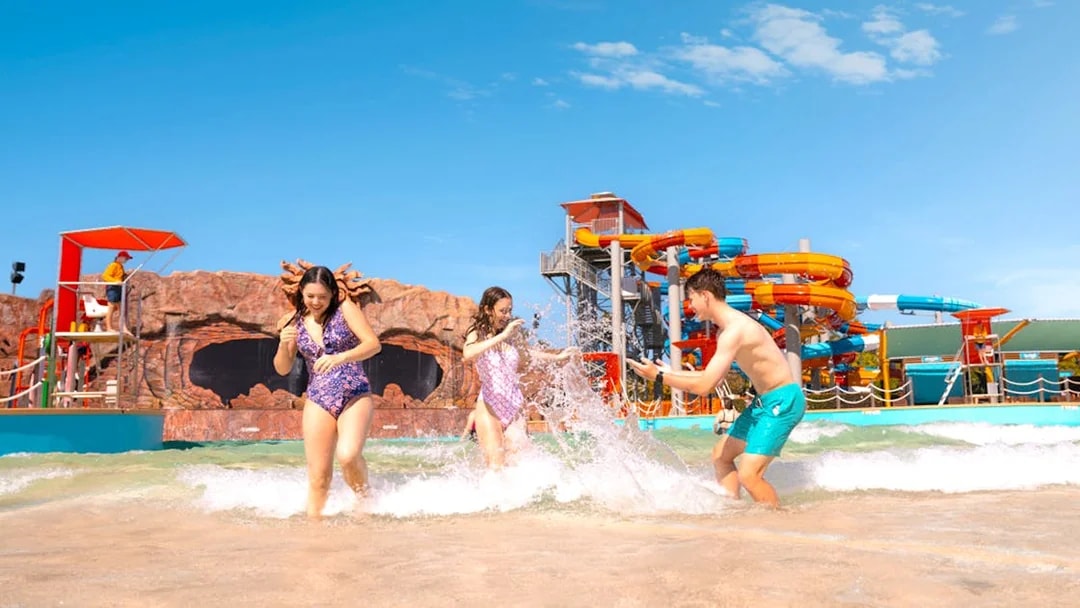 People enjoying the wave pool at Whitewater World with colorful slides in the background.