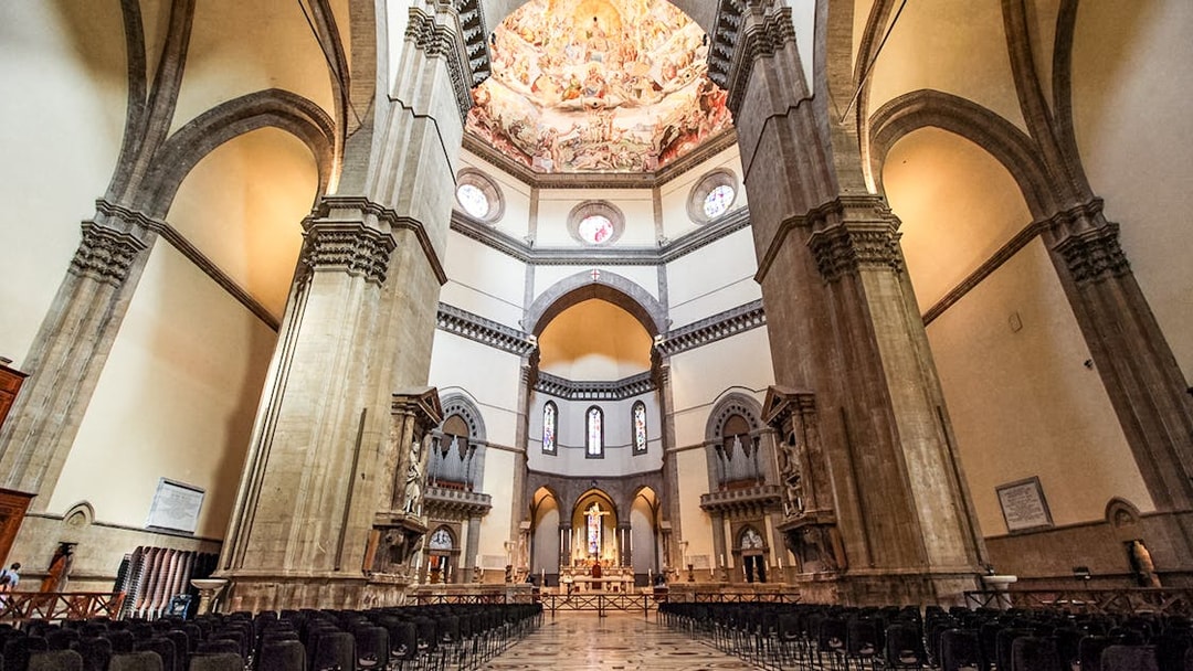 Florence Duomo interior with frescoed dome and rows of chairs.