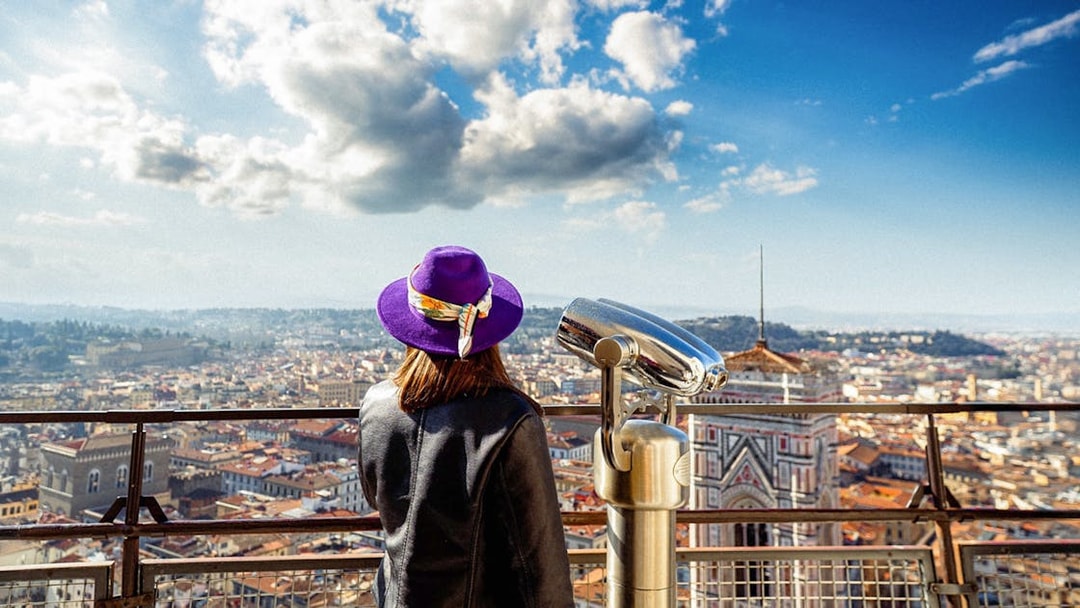 Girl viewing Florence from cathedral dome with cityscape and telescope.