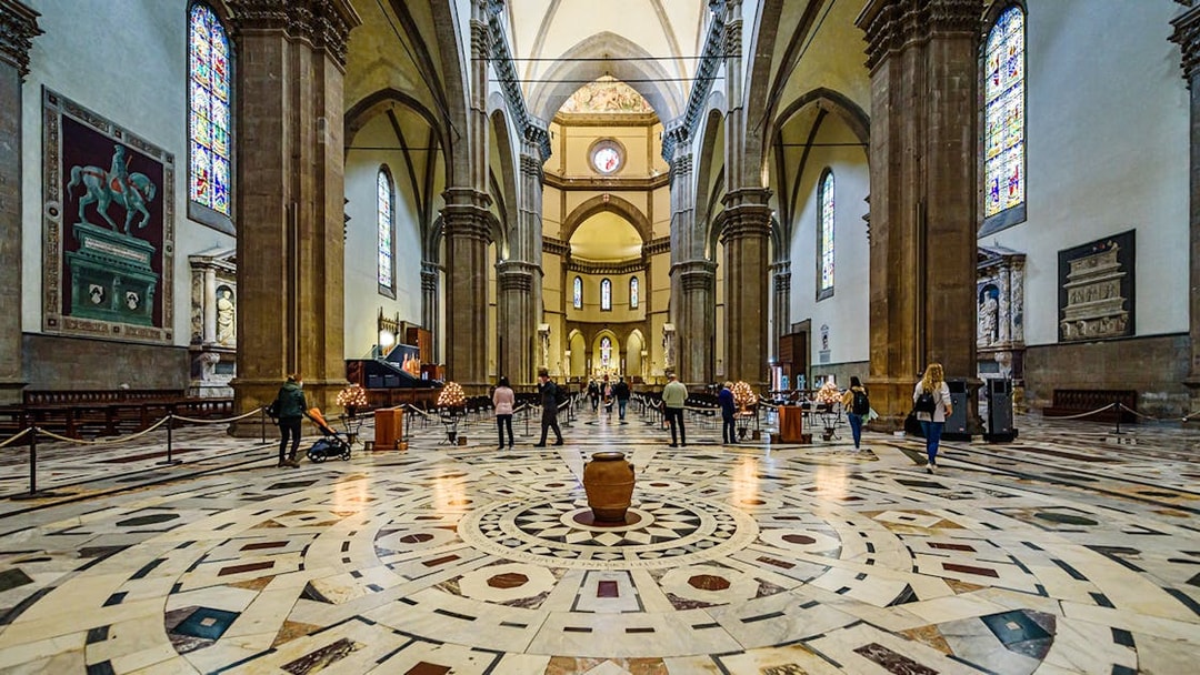 Interior view of Florence Cathedral with ornate marble floor and stained glass windows.