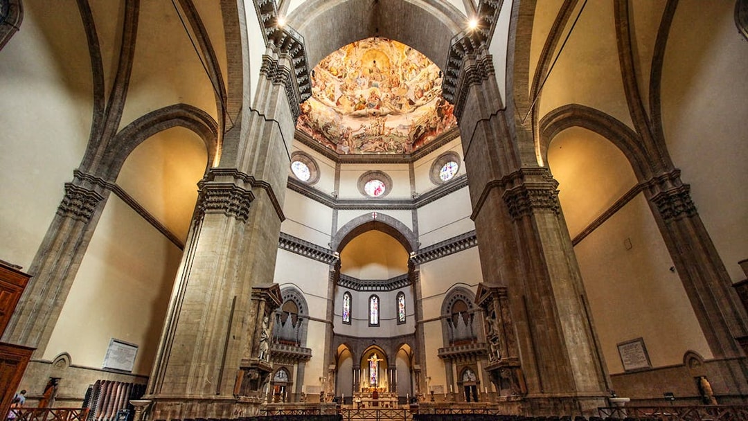 Interior of Cathedral of Santa Maria del Fiore, Florence, showcasing ornate dome frescoes and arches.