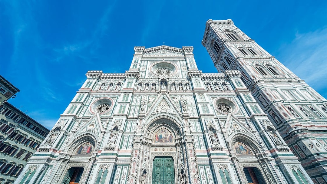 Duomo Florence facade with bell tower under blue sky.