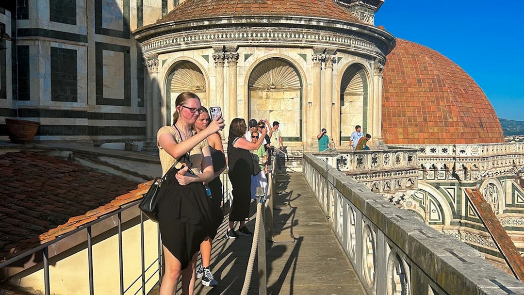 Tourists walking on Florence Duomo terrace, capturing views of the dome.