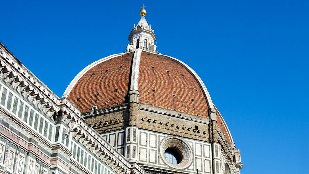 Florence Duomo's iconic red-tiled dome against a clear blue sky.