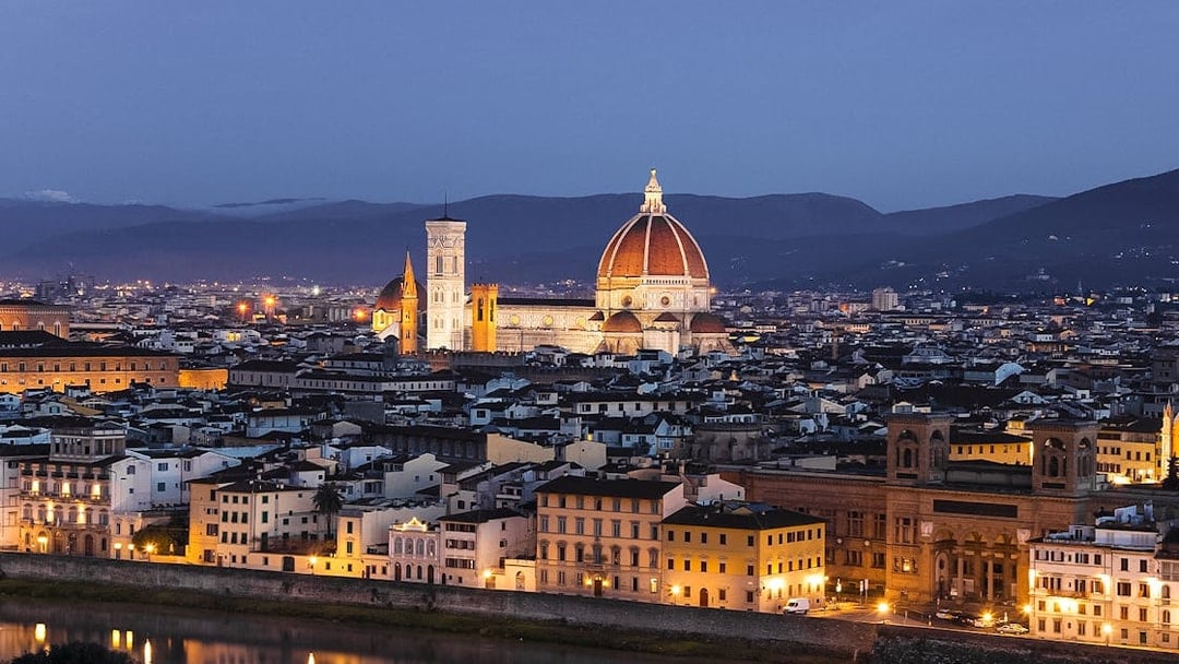 Florence cityscape at night from Piazzale Michelangelo, featuring the illuminated Duomo.