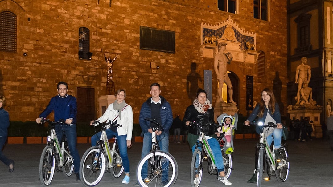 Group on e-bikes in front of Palazzo Vecchio during Florence night tour.