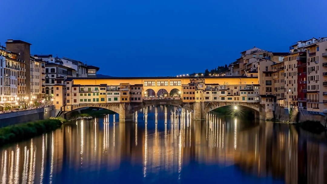Ponte Vecchio illuminated at night over the Arno River in Florence, Italy.
