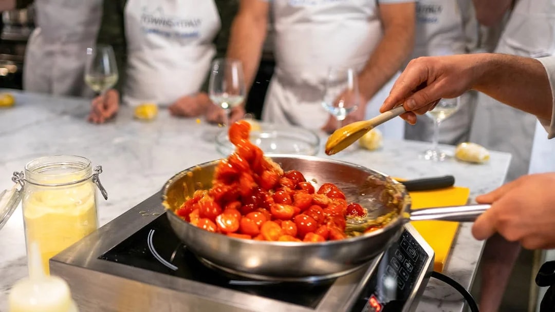 Cooking cherry tomatoes in a pan during a Florence pasta-making class.