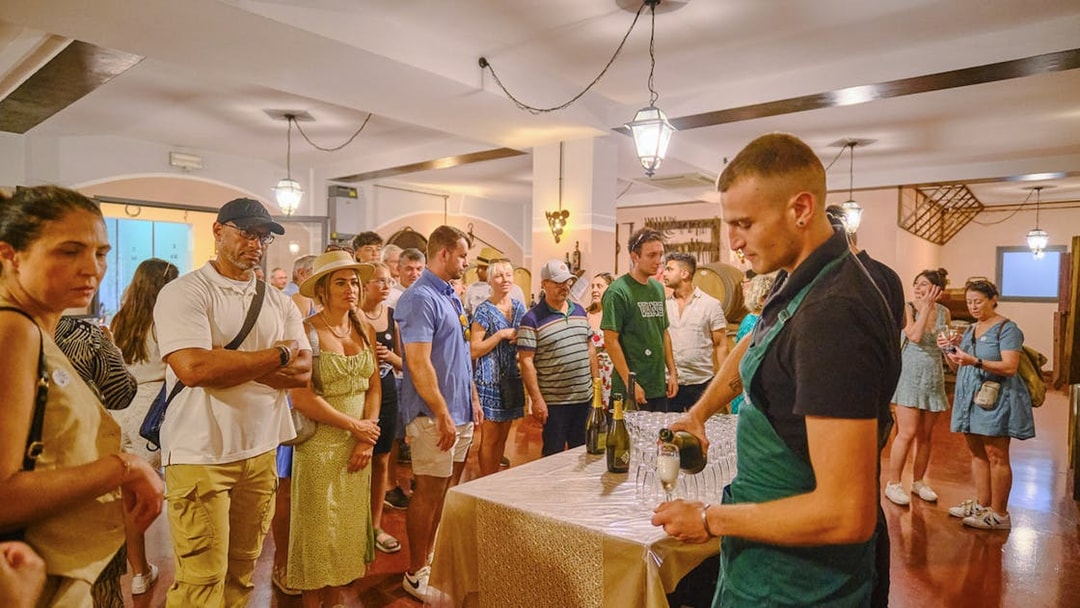 Tourists enjoying a wine tasting experience in Tuscany during a Pisa, Siena, and San Gimignano day trip.
