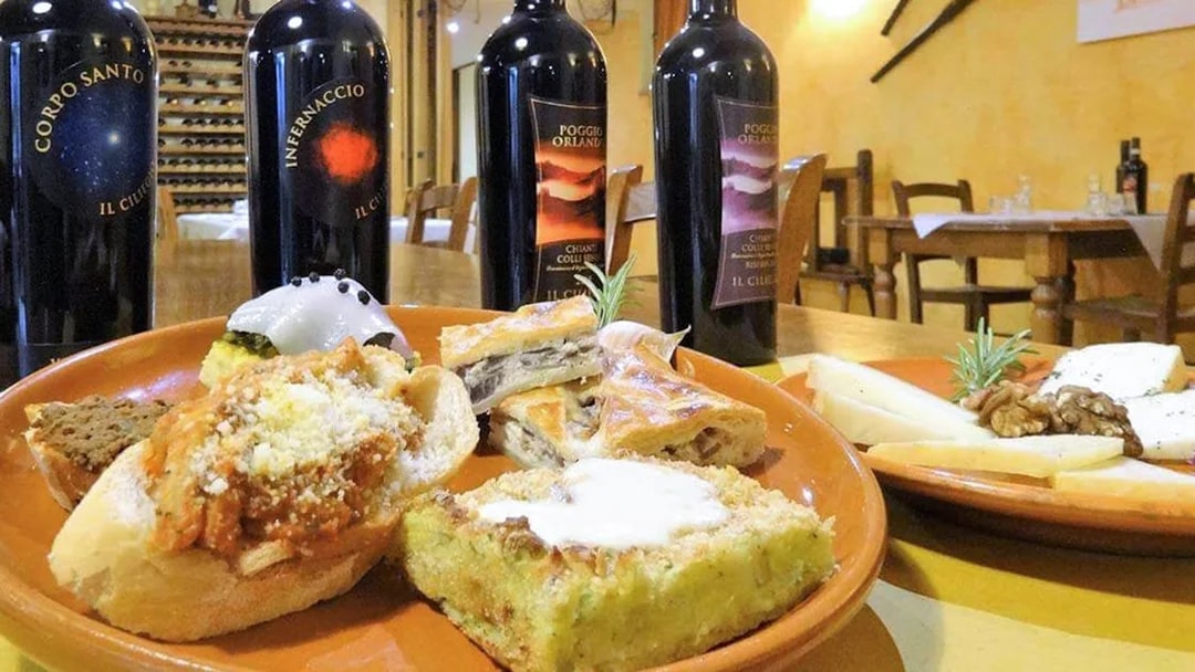 Wine bottles and Italian appetizers on a table during a Pisa, Siena, San Gimignano & Chianti day trip.