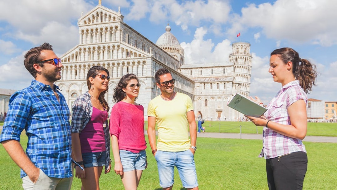 Tour guide explaining the Leaning Tower of Pisa to visitors.