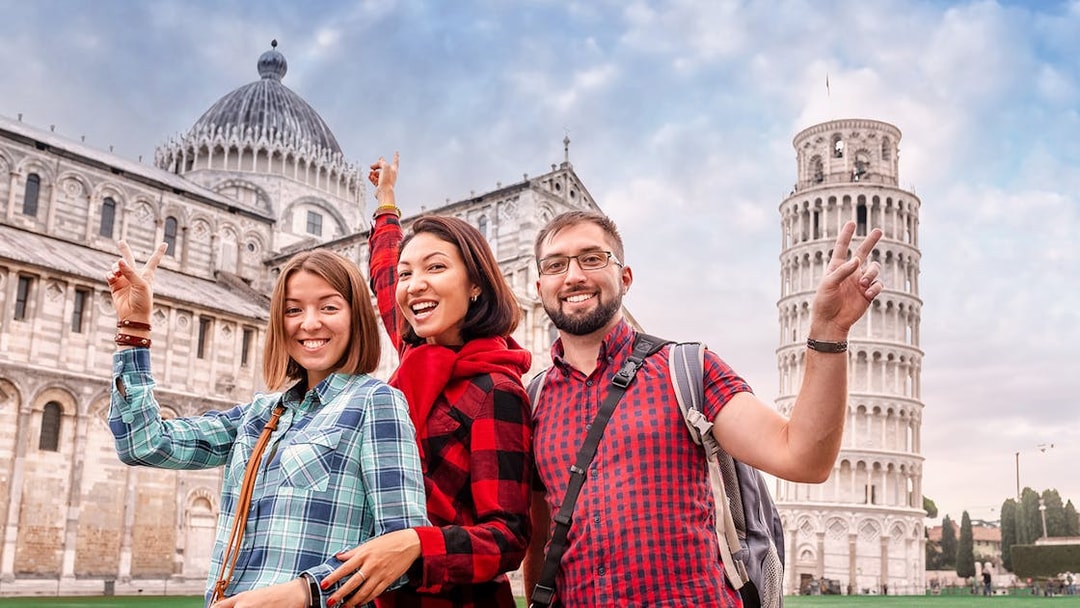 Tourists posing in front of the Leaning Tower of Pisa during a guided tour from Florence.