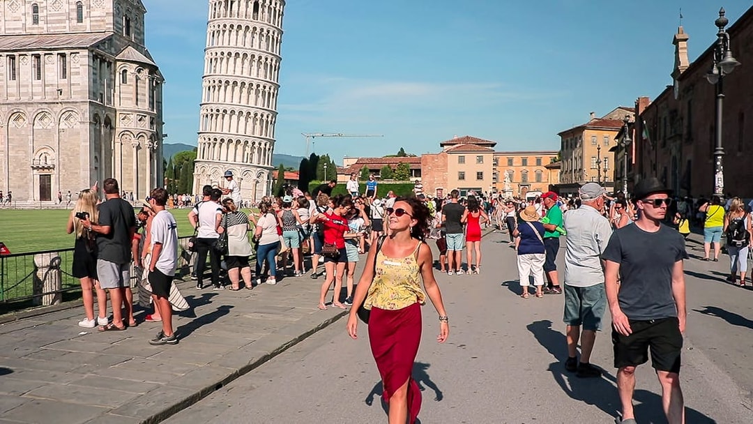 Tourists exploring Piazza dei Miracoli with the Leaning Tower of Pisa in the background.
