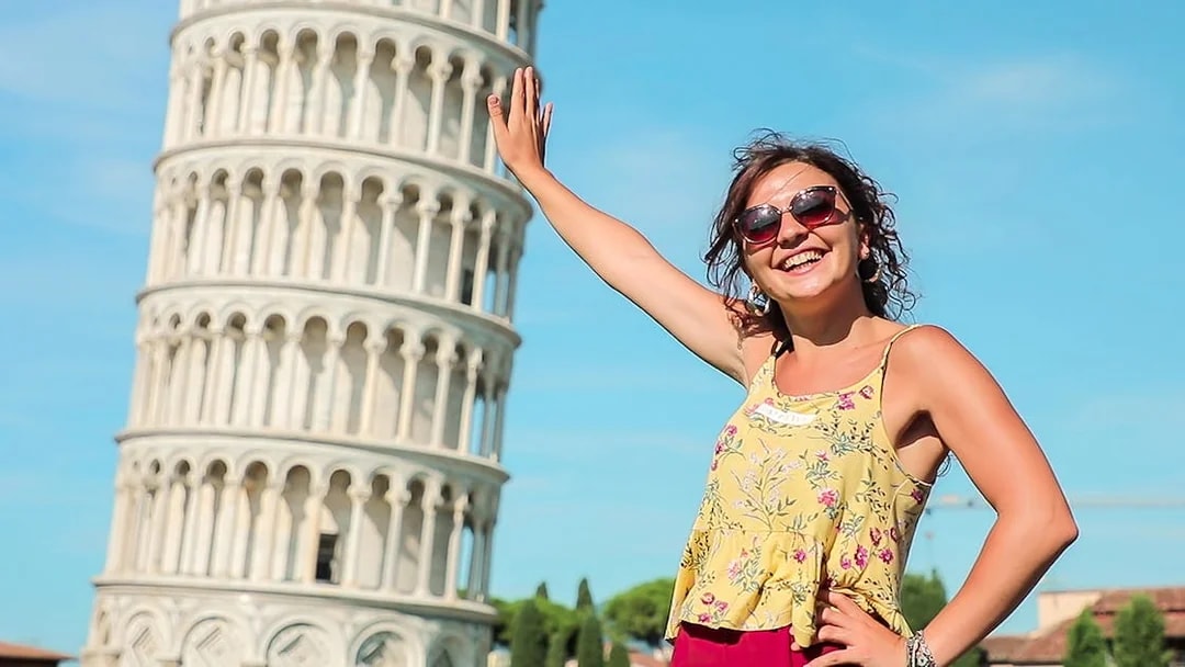 Smiling tourist posing with the Leaning Tower of Pisa during a guided tour from Florence.