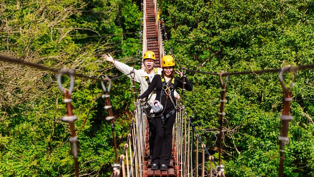 Two people crossing a suspension bridge during Flying Hanuman zipline adventure in Phuket.
