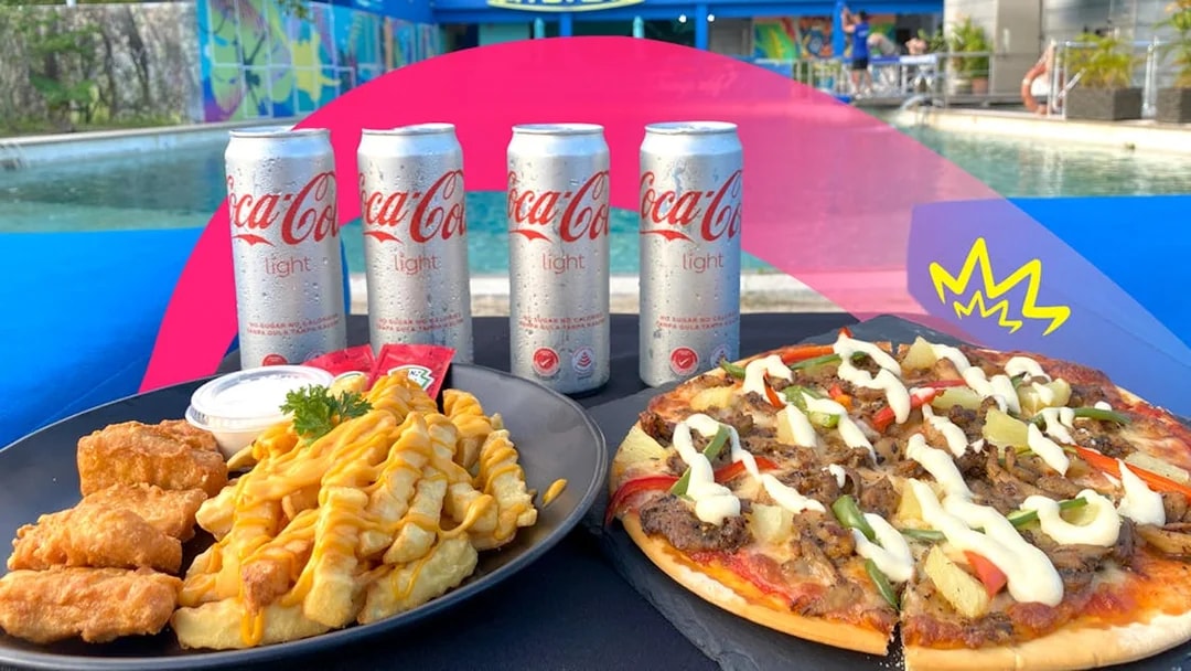 Pizza and fries with chicken by a pool, part of Food Discovery Pass experience.