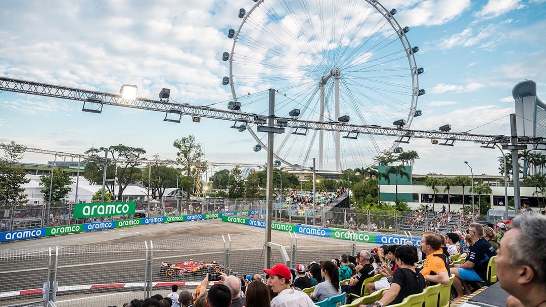 Formula 1 race at Singapore Grand Prix 2025 with Singapore Flyer in background.