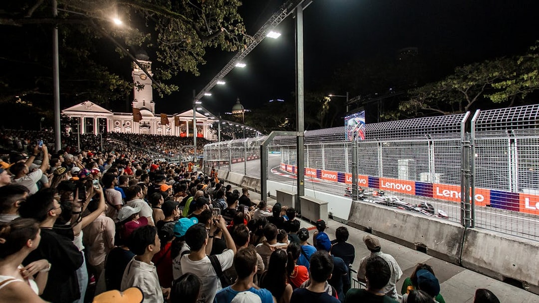 Spectators watching F1 race at Zone 4 Walkabout, Singapore, with cars on track.
