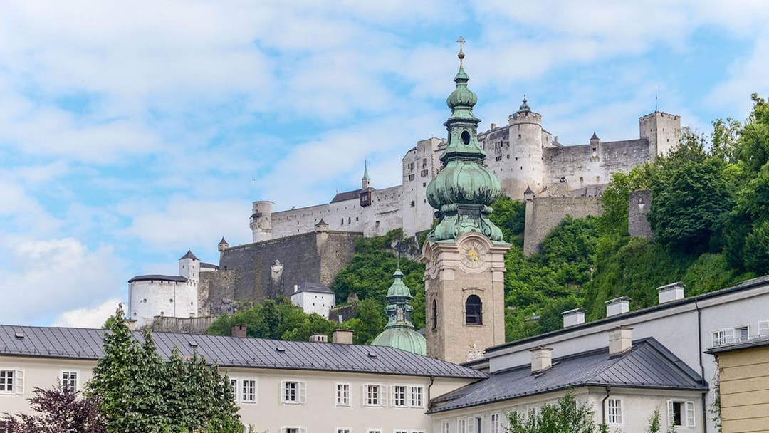 St Peters Abbey and Hohensalzburg Castle in Salzburg, Austria, with lush greenery.