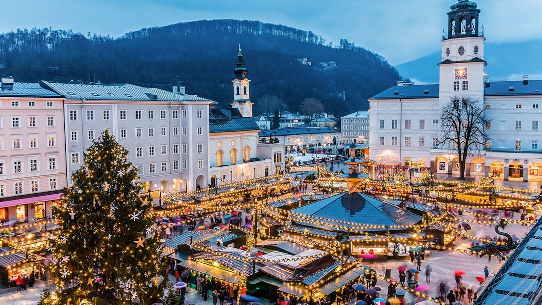 Salzburg Christmas market with festive lights and Fortress Hohensalzburg in the background.
