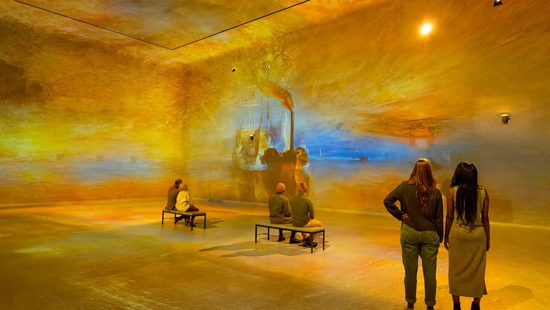 Visitors viewing immersive art projections at Frameless London exhibition.