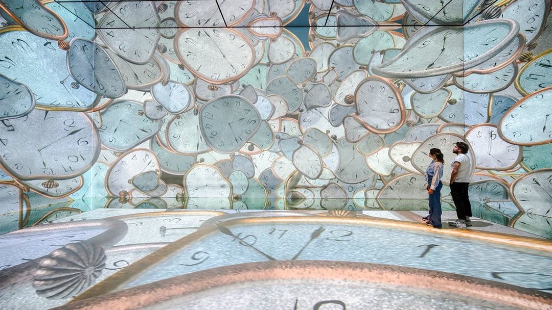 Visitors exploring melting clock projections at Frameless London immersive art exhibit.