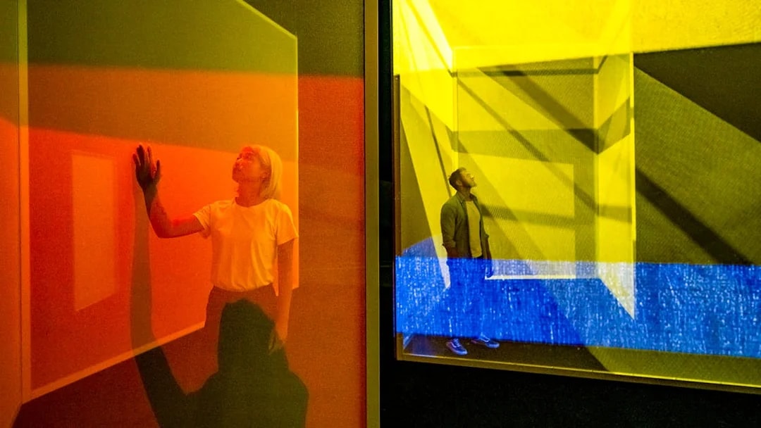 Visitors exploring colorful light installations at Frameless London exhibit.