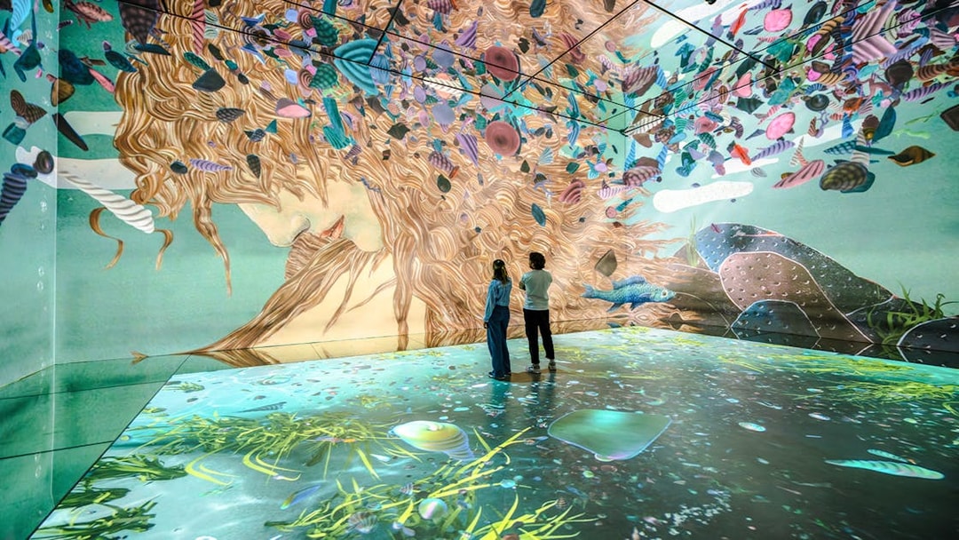 Visitors exploring immersive art projections at Frameless London exhibit.