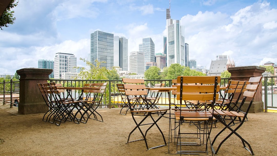 Cafe tables and chairs overlooking Frankfurt cityscape with skyscrapers.