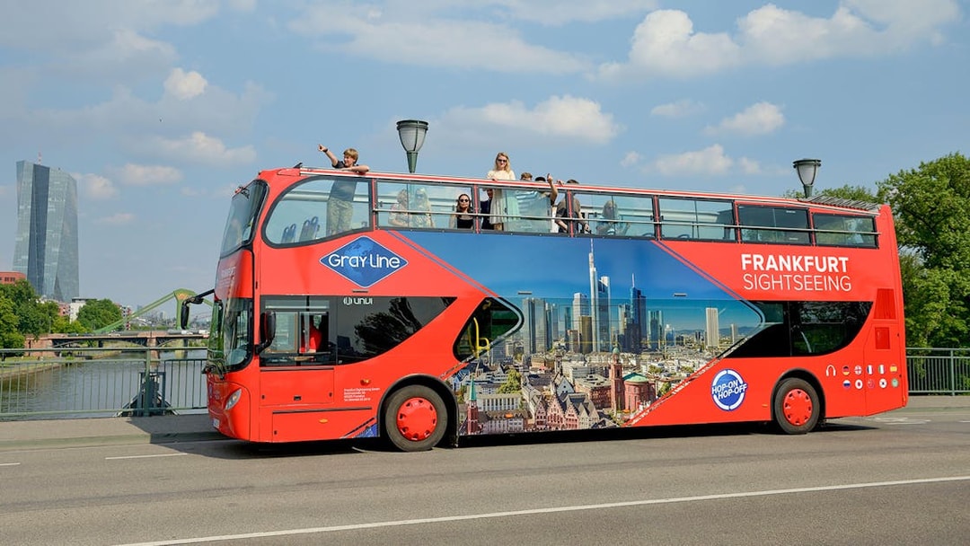Frankfurt sightseeing bus on a bridge with skyline in the background.