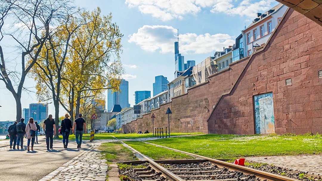People walking along a path with Frankfurt skyline in the background, part of Skyline Hop-On Hop-Off tour.