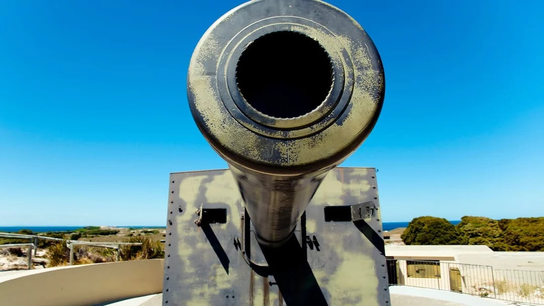 Historic coastal artillery cannon overlooking ocean and landscape.