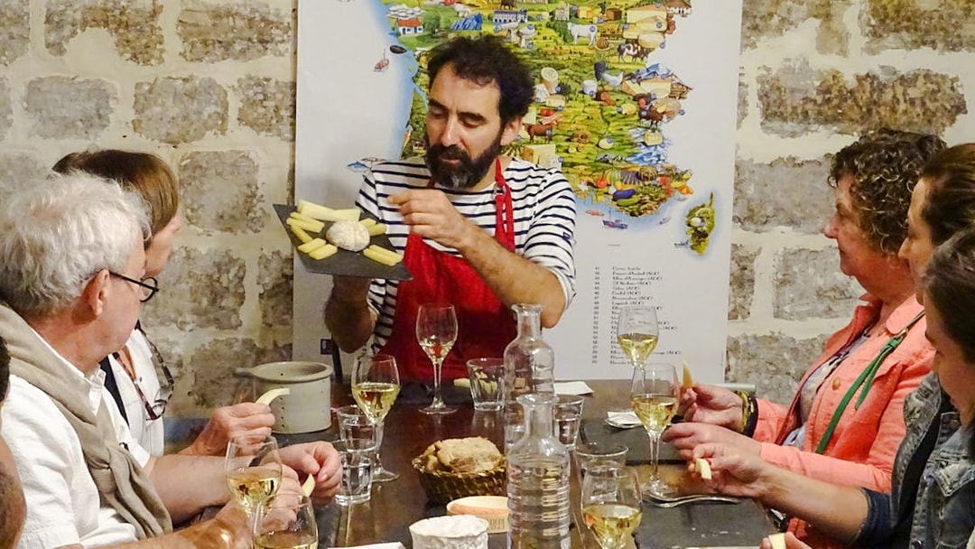 Expert discussing cheese varieties at Cheese Museum Paris, France with visitors seated around a table.