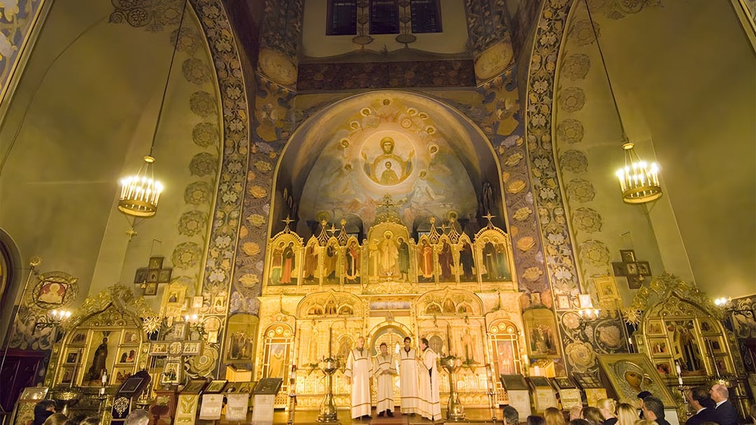 Interior of a richly decorated church in the French Riviera, featuring ornate icons and a congregation.