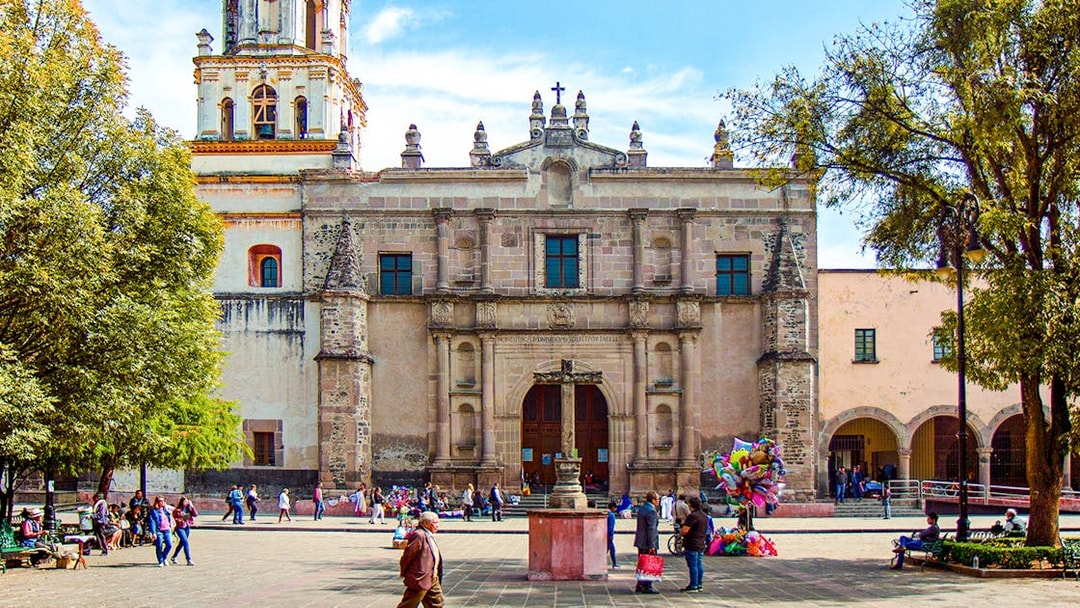 Parroquia San Juan Bautista facade with people in plaza, Mexico.