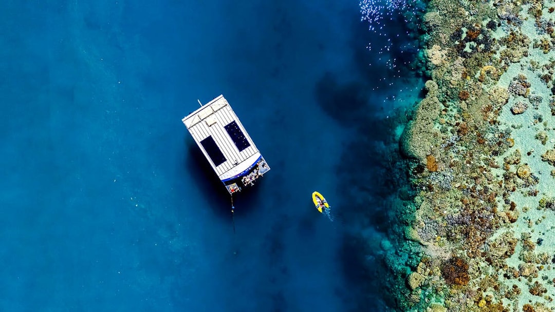 Glass bottom boat near coral reef at Airlie Beach, with a kayak nearby.